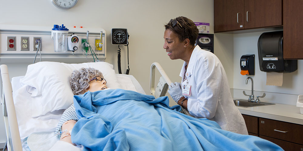 Professor talks to patient during Nursing HITS lab simulation.